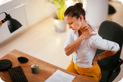 Woman at desk in back pain.
