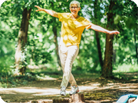 Older woman performing balance exercised outdoors.