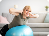 Middle-aged women strengthening her core by exercising on a fitness ball.