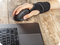 Man wearing a wrist brace while using computer.