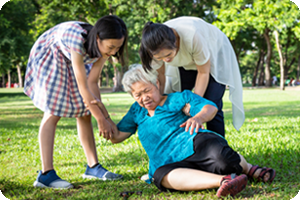 Elderly woman fallen in park. Two grandaughter help her to her feet.
