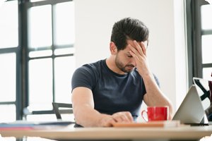 Man sitting at office desk with migraine headache.