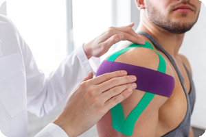 A PT kinesio taping an athlete's shoulder.